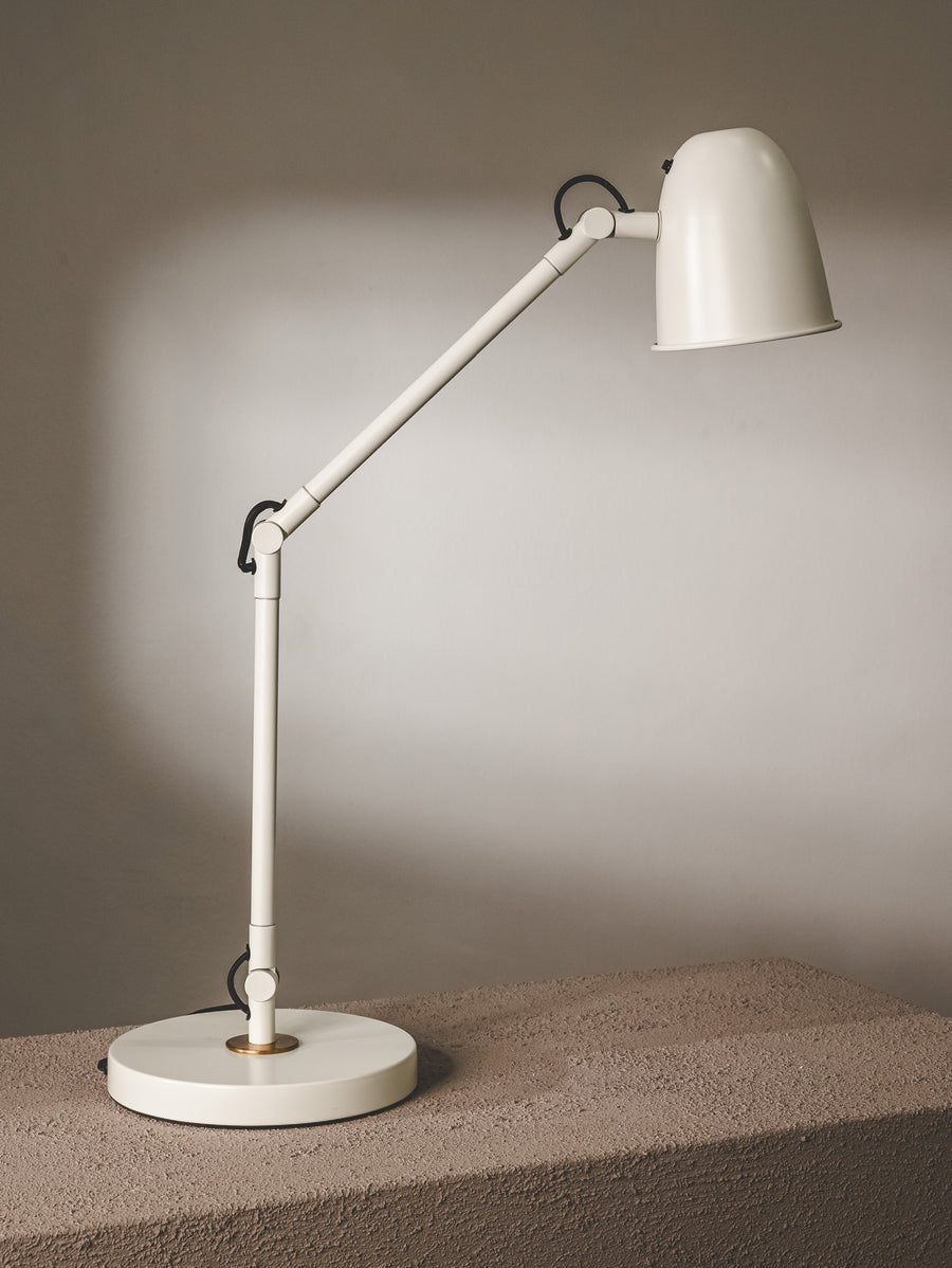 Desk lamp made of steel and sporting an articulated arm with adjustable head in pearl white colourway.