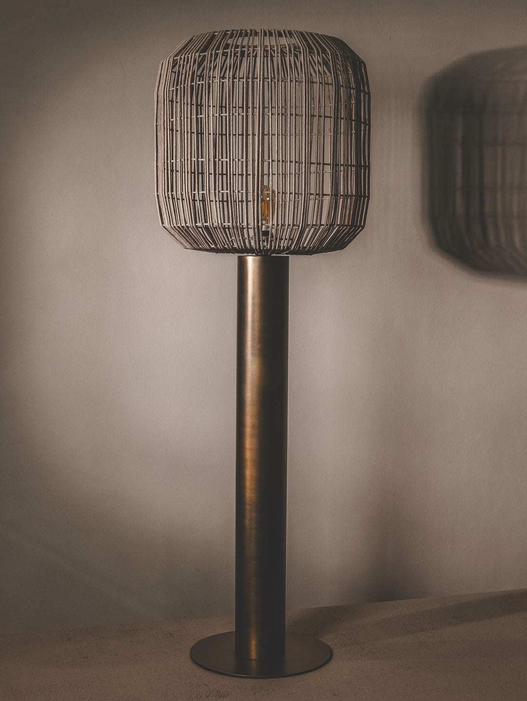 Floor lamp with steel base and shade made of handwoven rope.