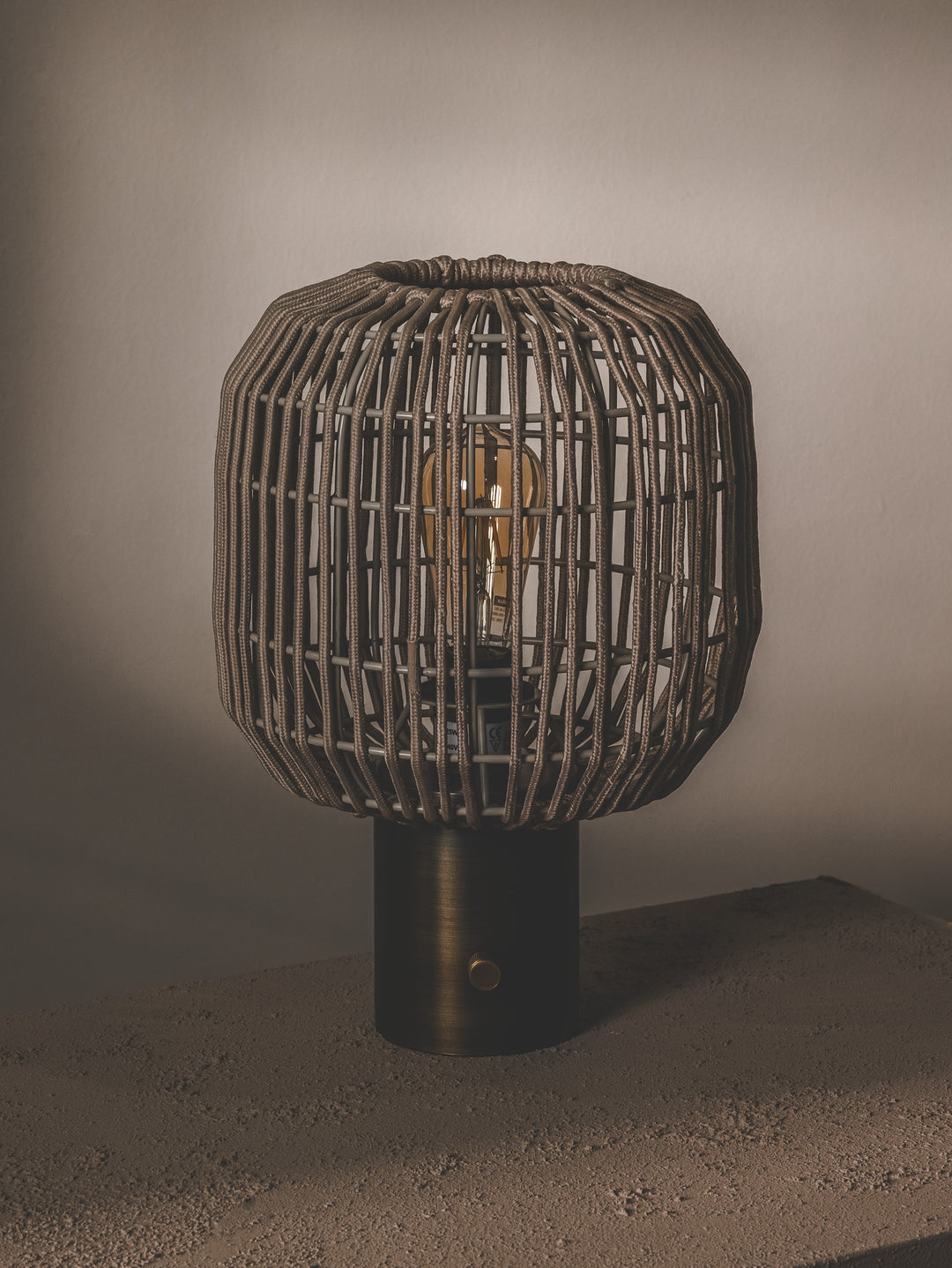 Table lamp with steel base and shade made of handwoven rope.