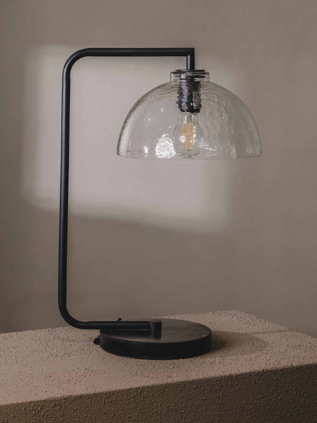 Table lamp with steel frame, glass shade and marble base in a black colourway.