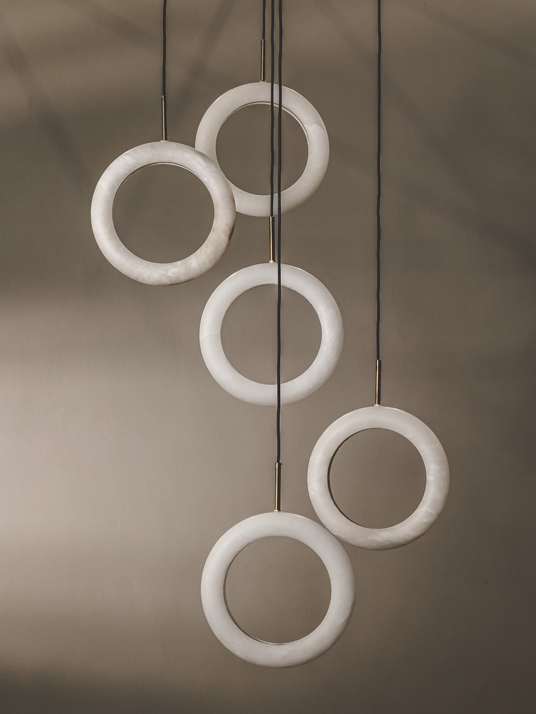 Multi-pendant that features light rings made from alabaster marble with arresting modern design.