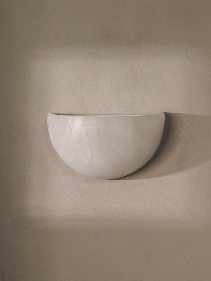 Handmade, moon-shaped alabaster wall light that mimics moonlight on a clear night.
