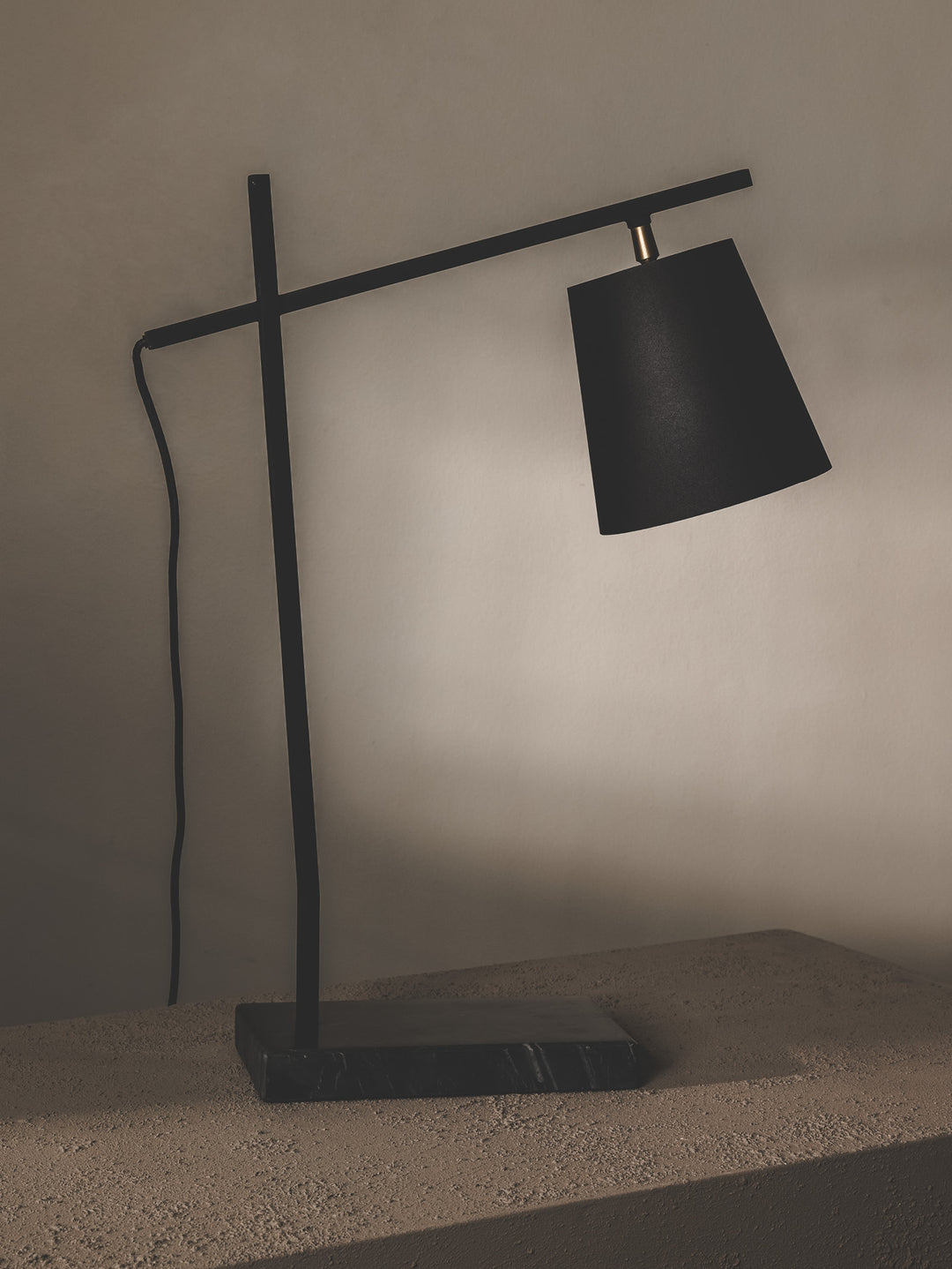 Minimalist table lamp made of steel and features brass details.