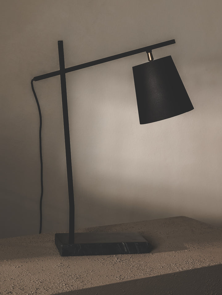 Minimalist table lamp made of steel and features brass details.