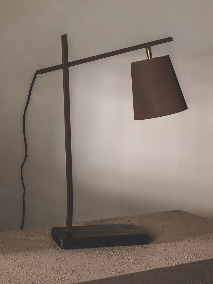 Minimalist table lamp made of steel and features brass details.