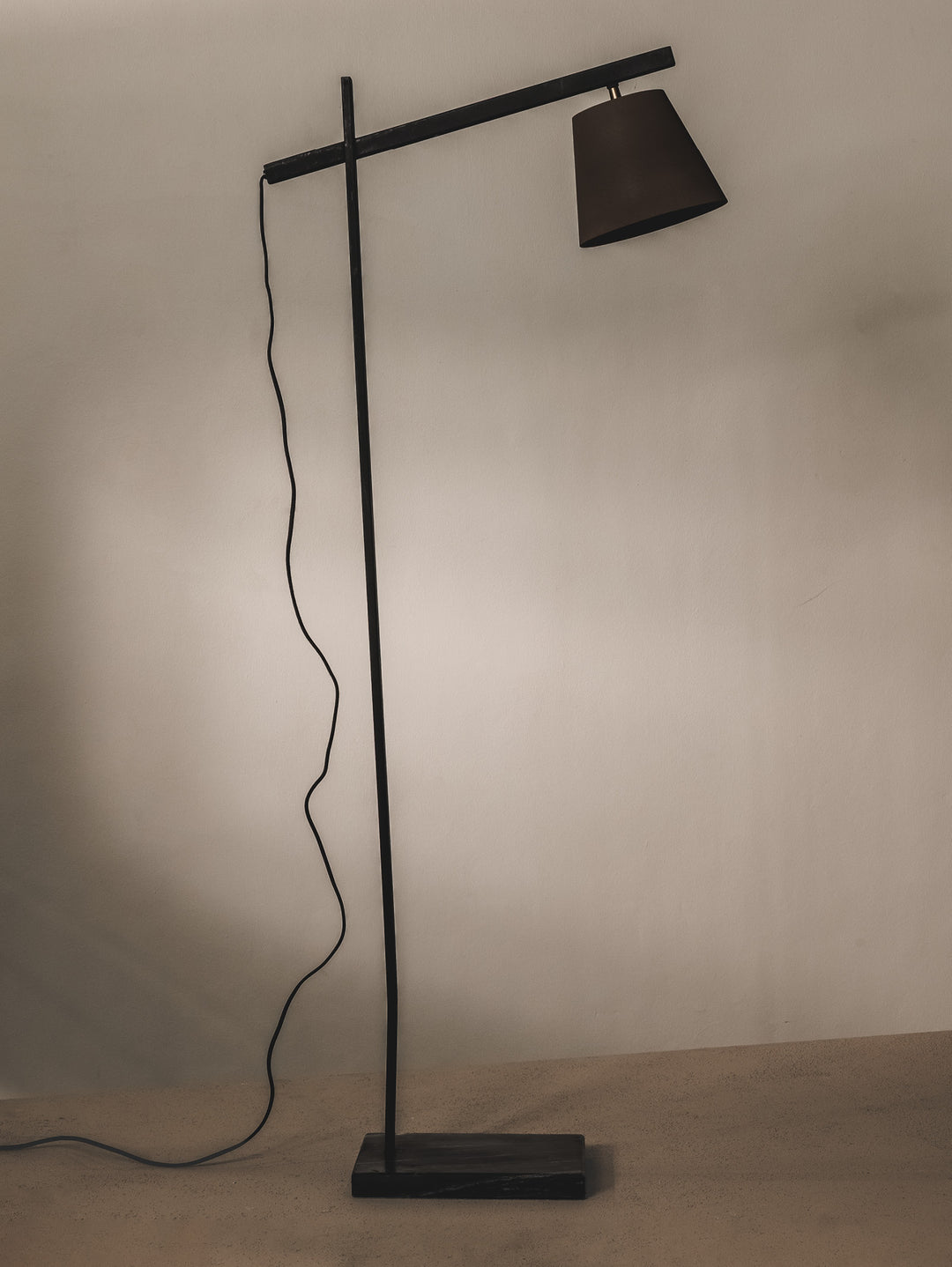 Minimalist floor lamp made of steel and features brass details.