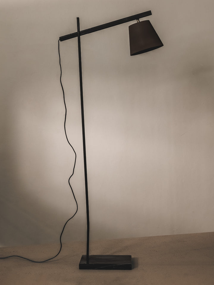 Minimalist floor lamp made of steel and features brass details.